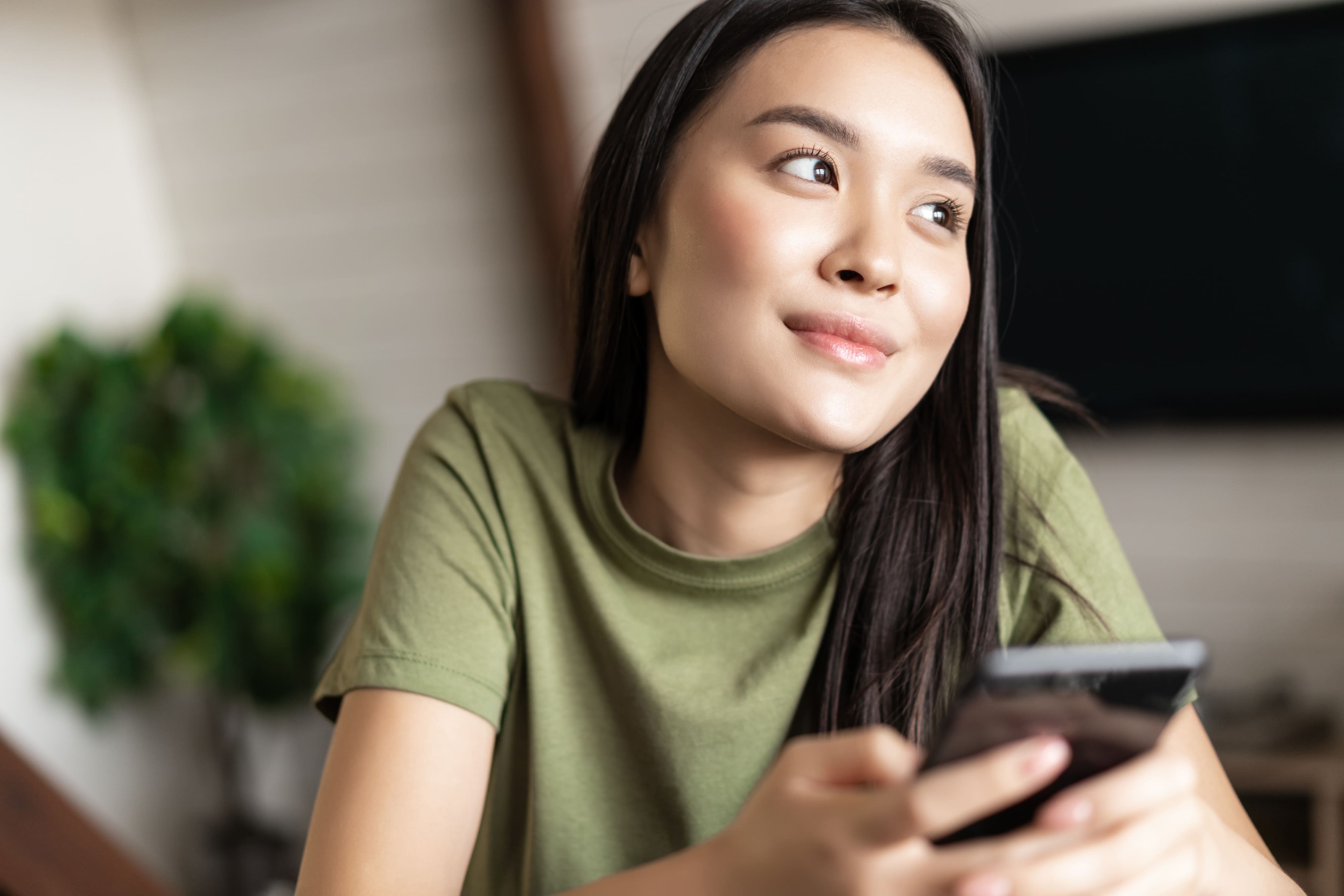 Jeune étudiante regardant l'écran du téléphone portable dans un salon